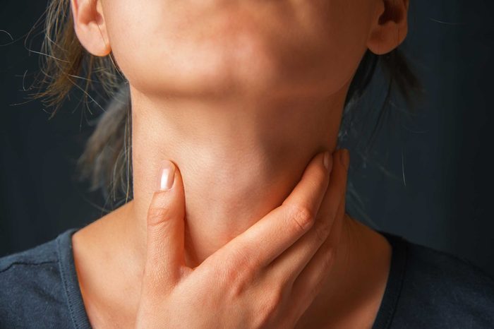 Woman holding her neck with her right hand.