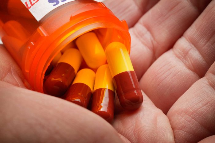 Bottle of pills opening up into a person's hand.