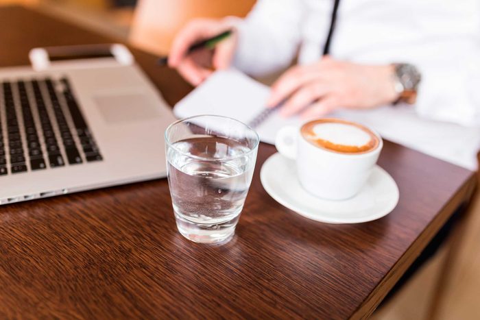 person at laptop computer with coffee and glass of water