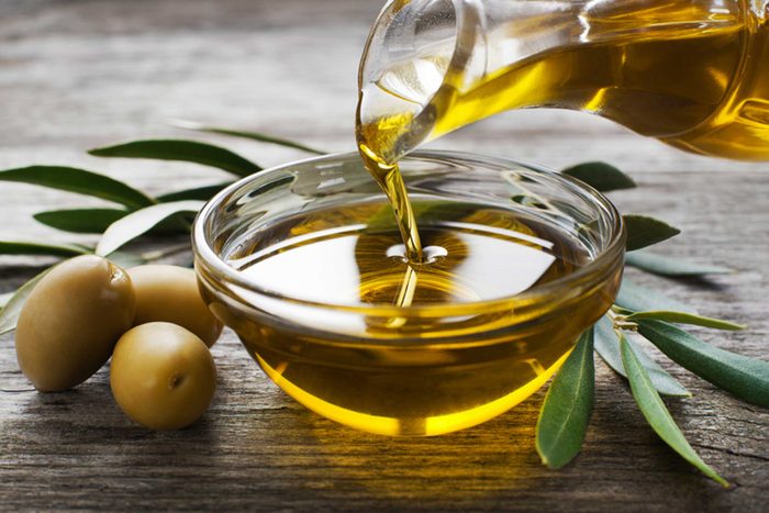 oil pouring into dish with olives