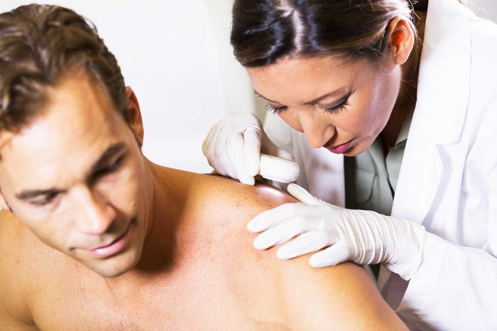 Doctor examining a man's back in the doctor's office.