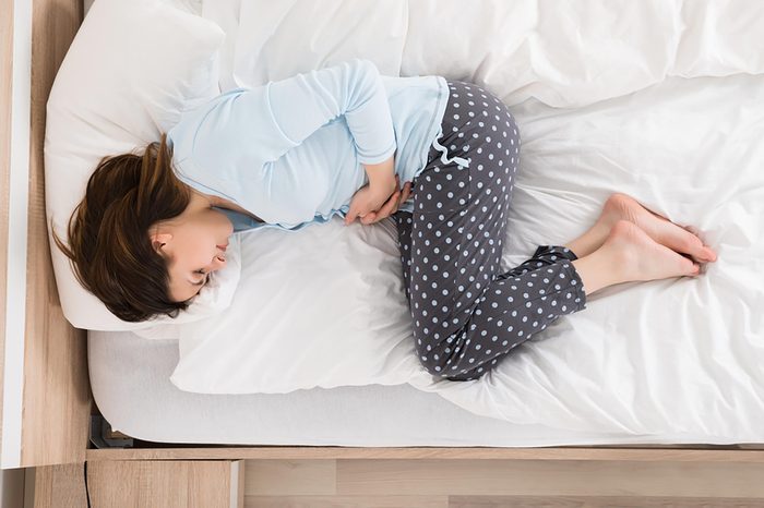 woman on her side in bed holding her stomach