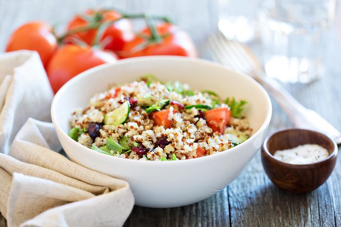 Bowl of quinoa topped with tomato and avocado.