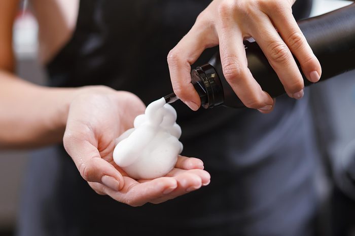 Woman applying hair product to her hands.