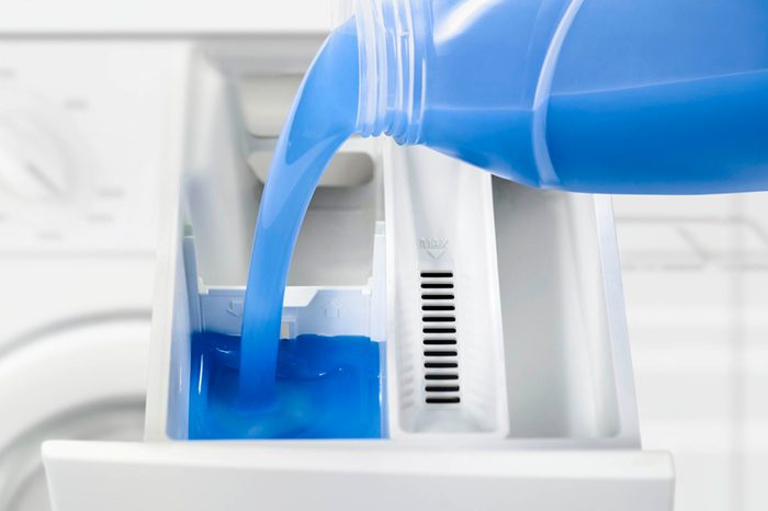 blue washing machine soap pouring into a washing machine soap applicator