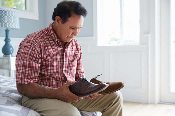 elderly man holding a pair of shoes 