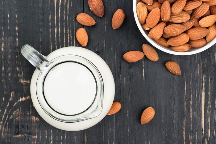 Bowl of almonds and a pitcher of milk on a table.