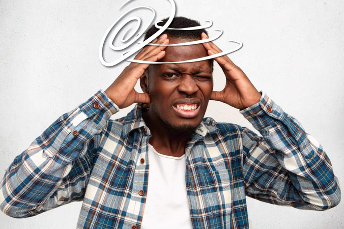 black man wincing in pain and holding his head