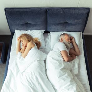 top view of couple sleeping back to back in bed